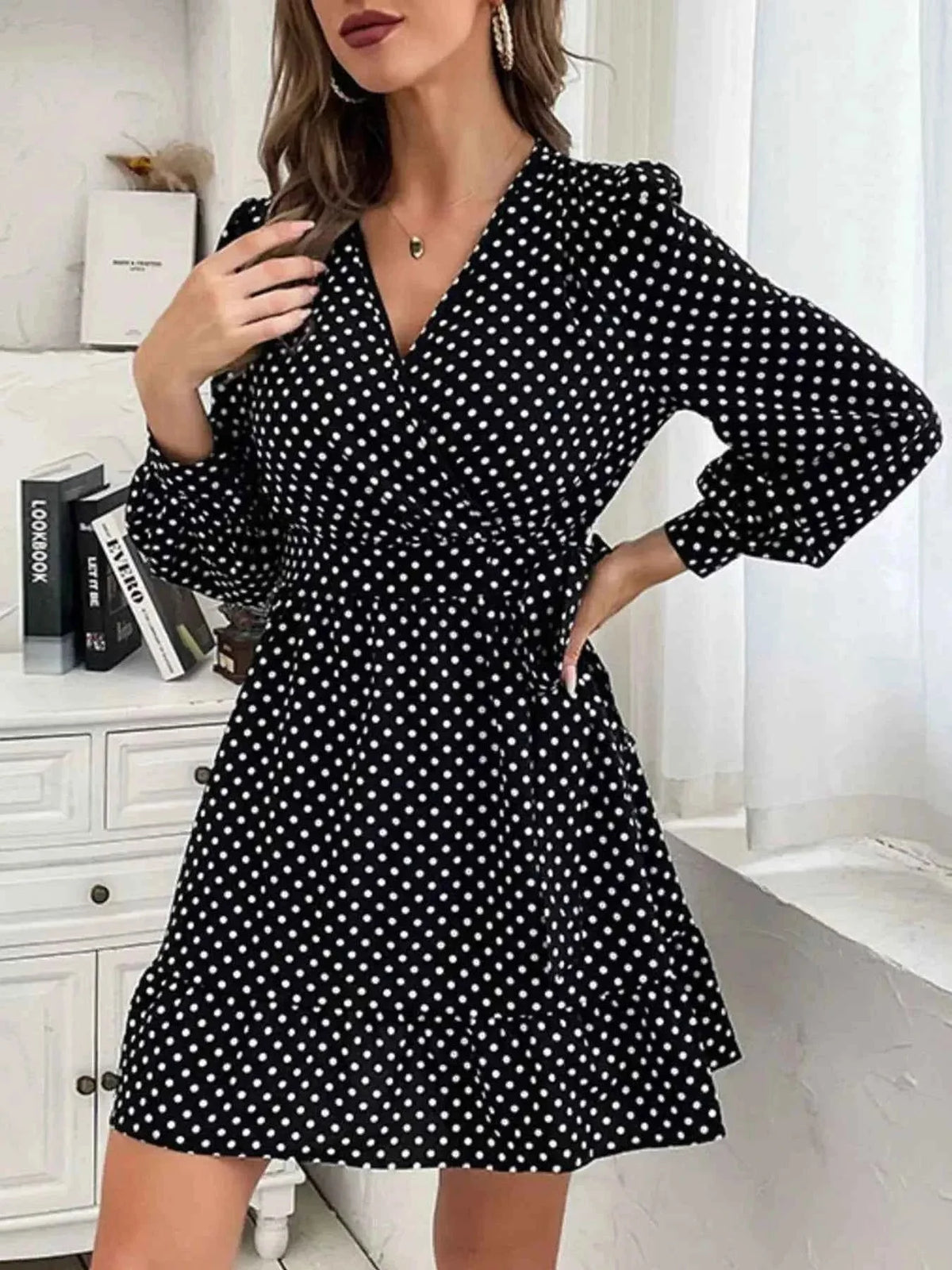 Polka Dot Wrap Mini Dress in black with white polka dots, long puff sleeves, V-neckline, ruffled hem, and tied waist detail.